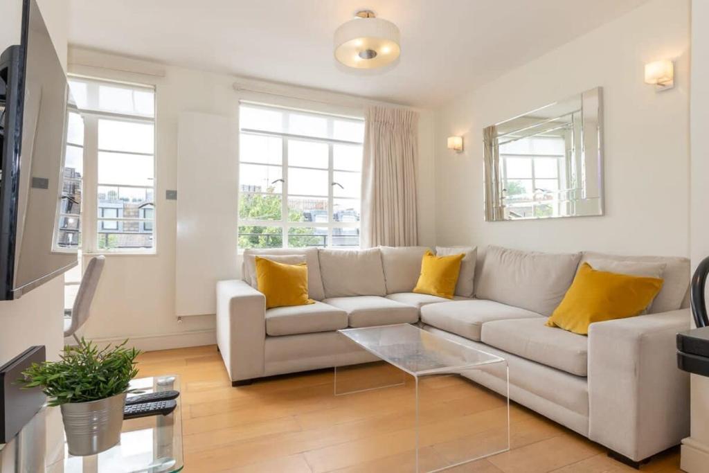 sala de estar con sofá blanco y almohadas amarillas en Bright & Spacious Top Floor Apartment in Chelsea, en Londres