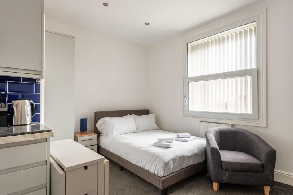 ein Schlafzimmer mit einem Bett, einem Stuhl und einem Fenster in der Unterkunft Modern and Cosy Budget Studio in Central Doncaster in Doncaster