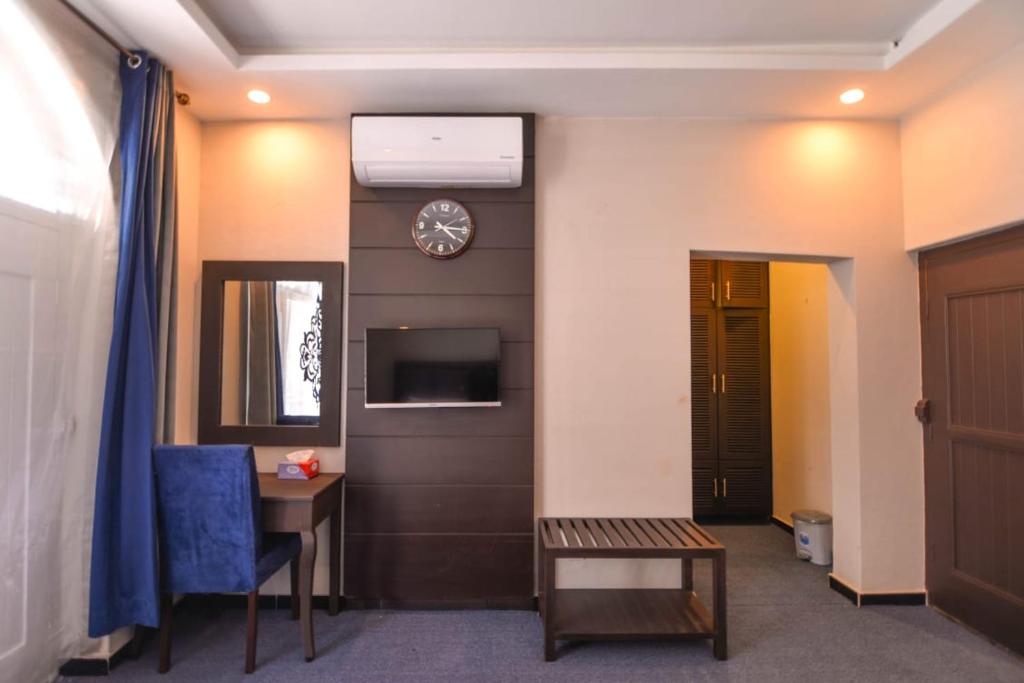 una habitación con un reloj en la pared y una mesa en Kallisto Hotel, en Gilgit