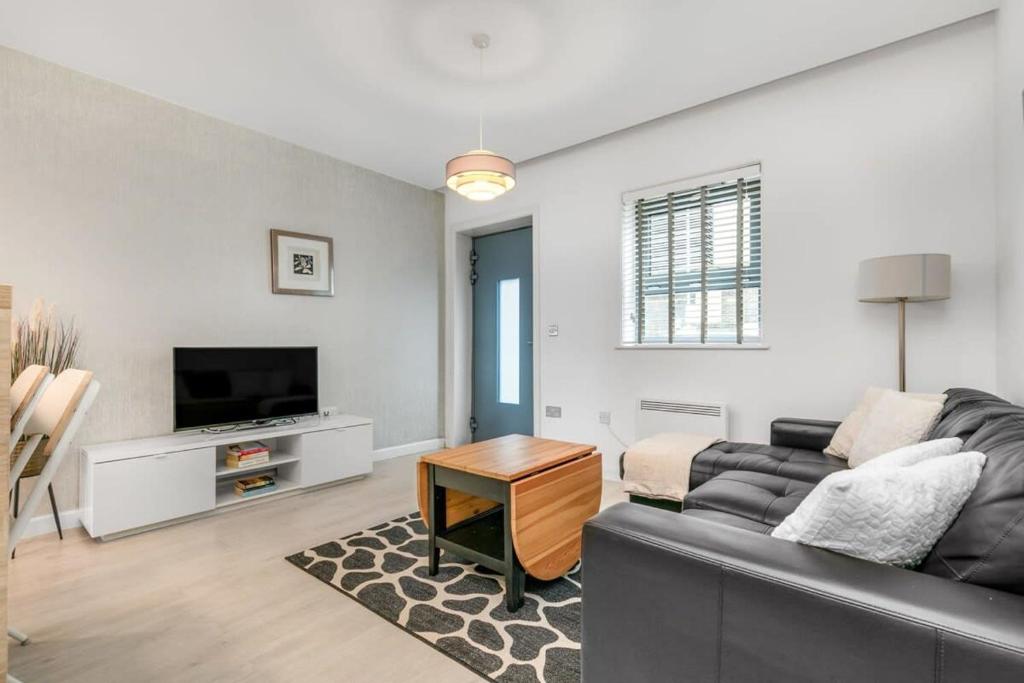 ein Wohnzimmer mit einem Sofa und einem TV in der Unterkunft Stylish 1 Bedroom Apartment in Central Woking in Woking