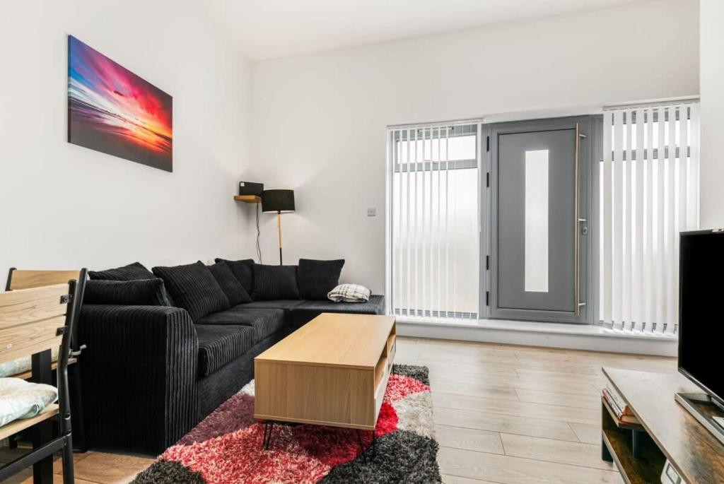 a living room with a black couch and a table at Lovely 1 Bedroom Apartment in Woking Centre in Woking