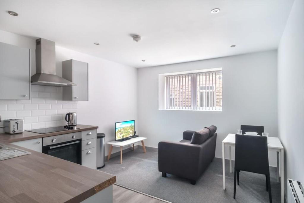 Cosy 1 Bed Apartment in Central Blackburn في بلاكبيرن: مطبخ وغرفة معيشة مع أريكة وطاولة