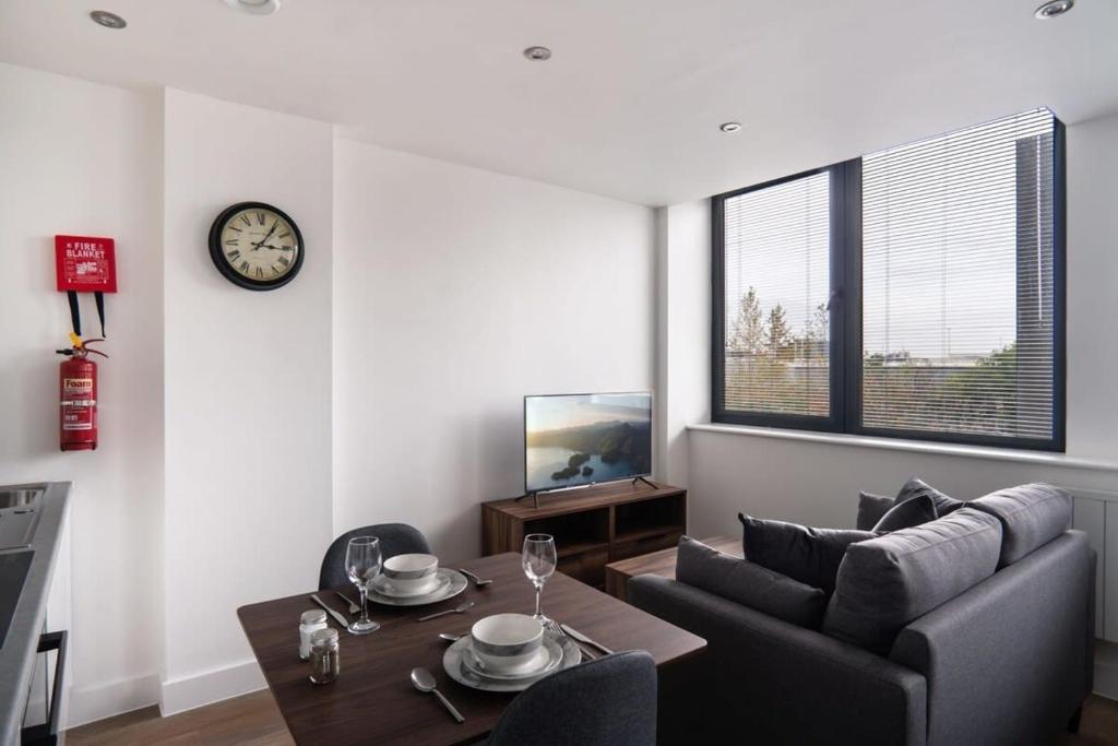 a living room with a couch and a table and a clock at Cosy Studio Apartment by Old Trafford in Manchester