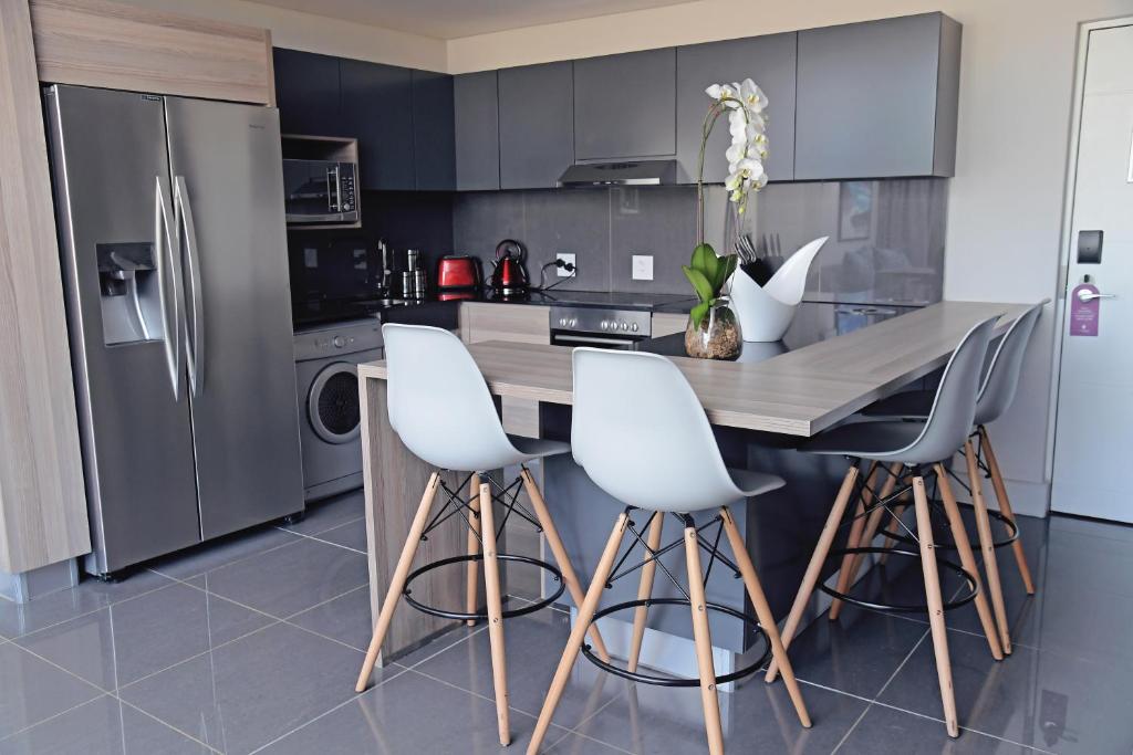uma cozinha com uma mesa de madeira e cadeiras brancas em The Capital Menlyn Maine em Pretoria