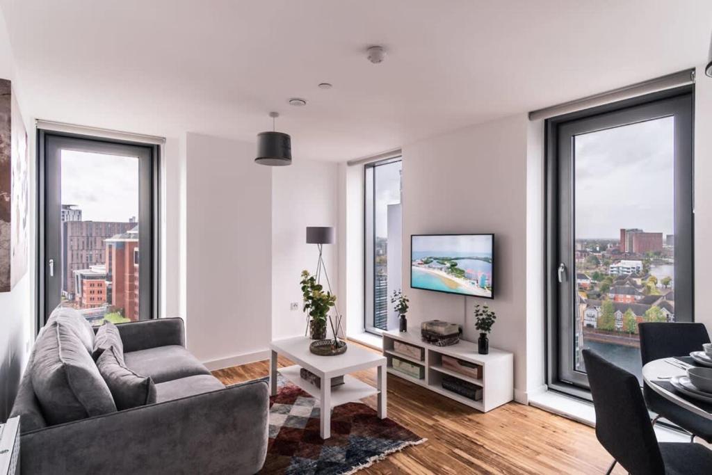 uma sala de estar com um sofá e uma televisão e janelas em 2 Bed Apartment in Media City, Amazing Views em Manchester