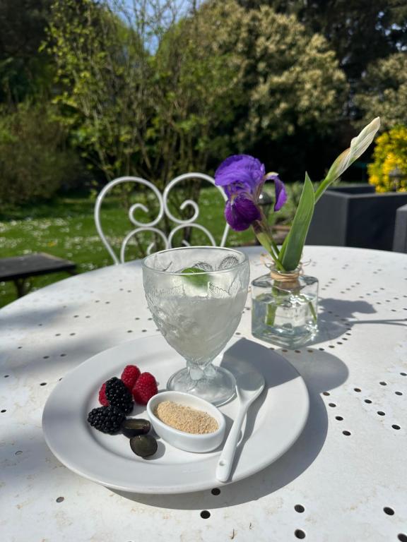 un plato de comida con bayas y un jarrón de flores en Chambres d'Hôtes de la Vallée Javot, en Féricy