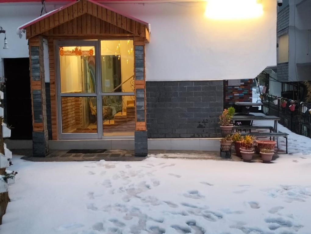 eine Haustür eines Hauses mit Schnee auf dem Boden in der Unterkunft Aman Inn in Dharamshala