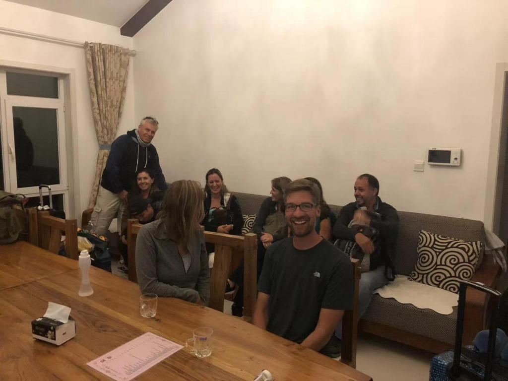 un gruppo di persone seduti intorno a un tavolo in una stanza di Beijing Mutianyu Great Wall Wangshanyuan Homestay a Huairou