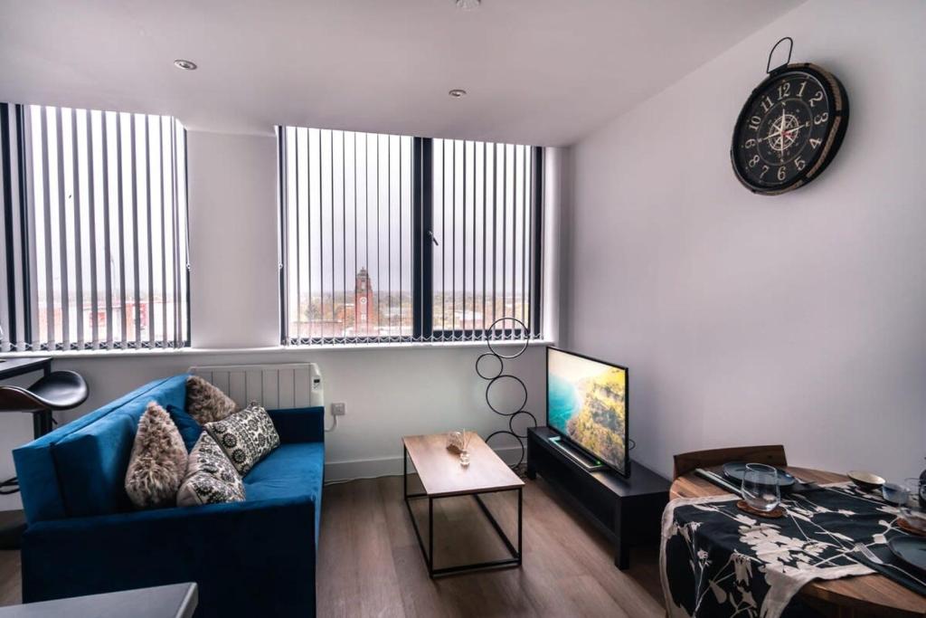 a living room with a blue couch and a clock at Modern Studio Apartment near Old Trafford in Manchester