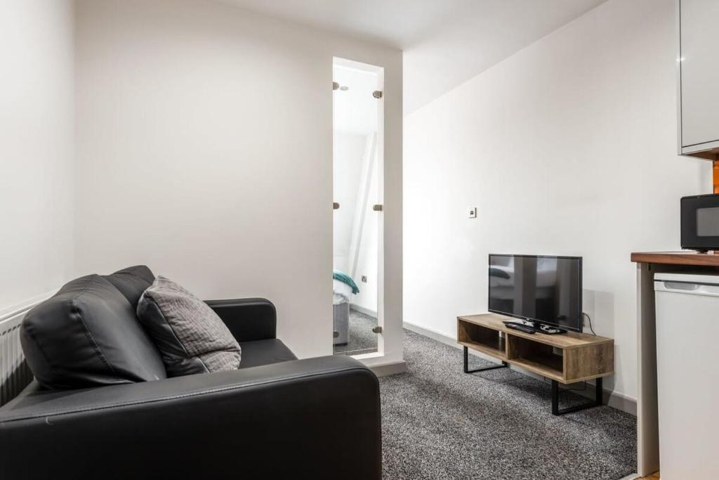 a living room with a black couch and a tv at Centrally Located 1 Bed Budget Flat in Halifax in Halifax