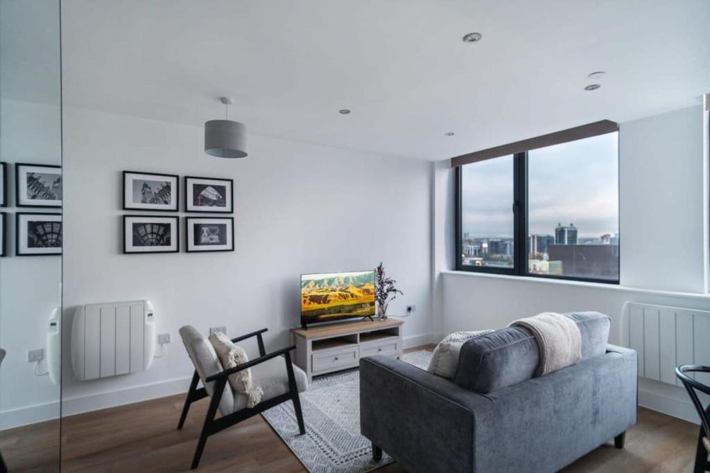 ein Wohnzimmer mit einem Sofa und einem TV in der Unterkunft Lovely Modern 1 Bed Apartment by Old Trafford in Manchester