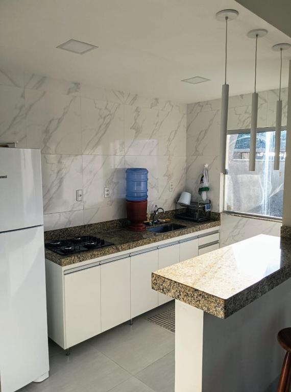 een keuken met witte kasten en een aanrecht bij Casa Luxo e Sossego 50m da Praia in Guriri