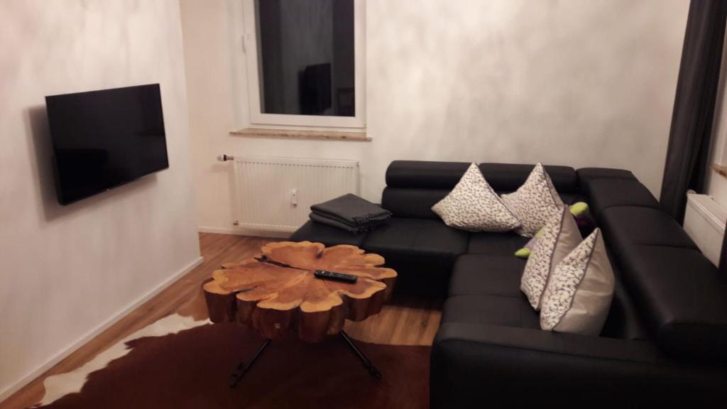 - un salon avec un canapé noir et une table dans l'établissement FeWo Wurmberg Domizil ZZ-BRAUNLAGE, à Braunlage
