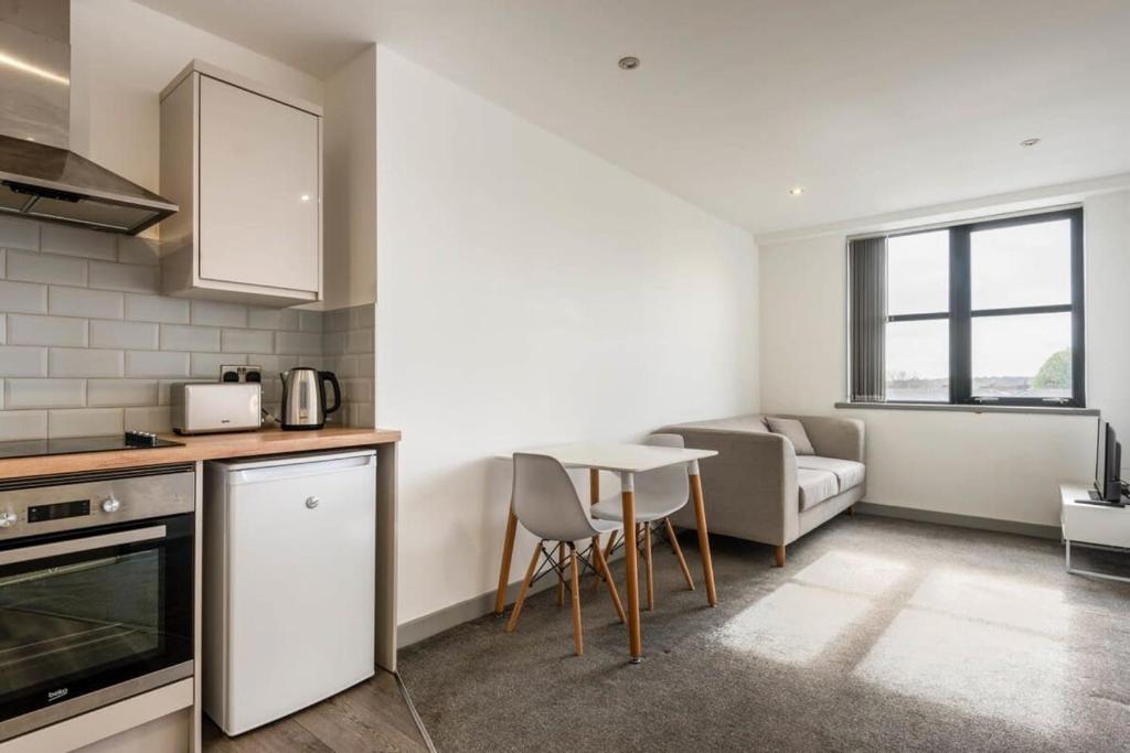 a kitchen and living room with a table and a couch at Modern 1 Bedroom Budget Apartment in Barnsley in Barnsley