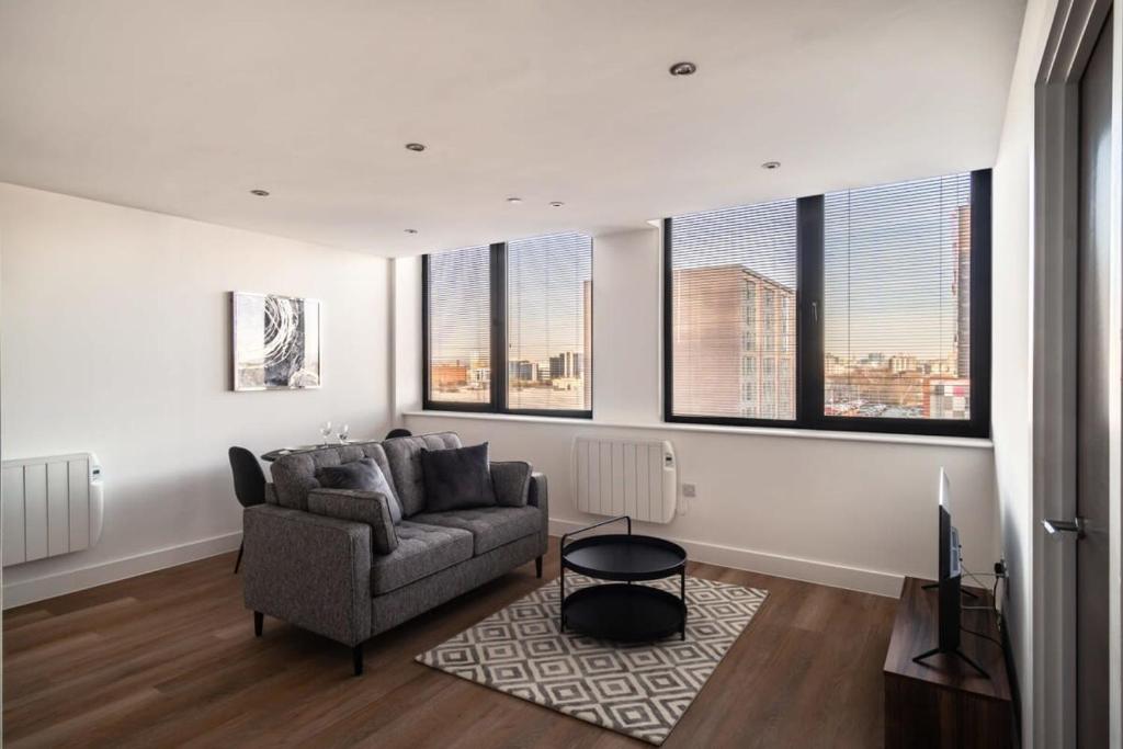 een woonkamer met een bank en een aantal ramen bij Modern & Spacious 1 Bed Apartment - Old Trafford in Manchester