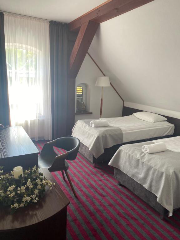 a hotel room with two beds and a chair at Bajkowy Zakątek in Gietrzwałd
