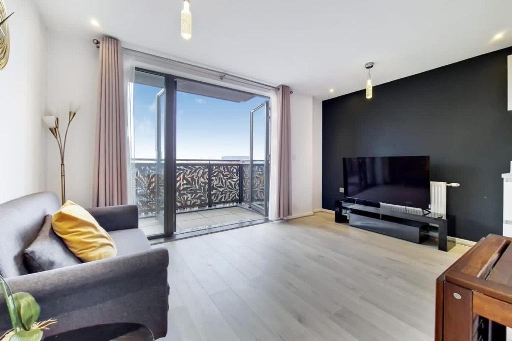 uma sala de estar com um sofá e uma televisão em Smart 1 Bedroom Apartment in Canning Town em Londres