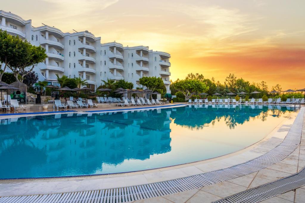 una piscina en un complejo al atardecer en Olbios Marina Resort Hotel, en Kumkuyu