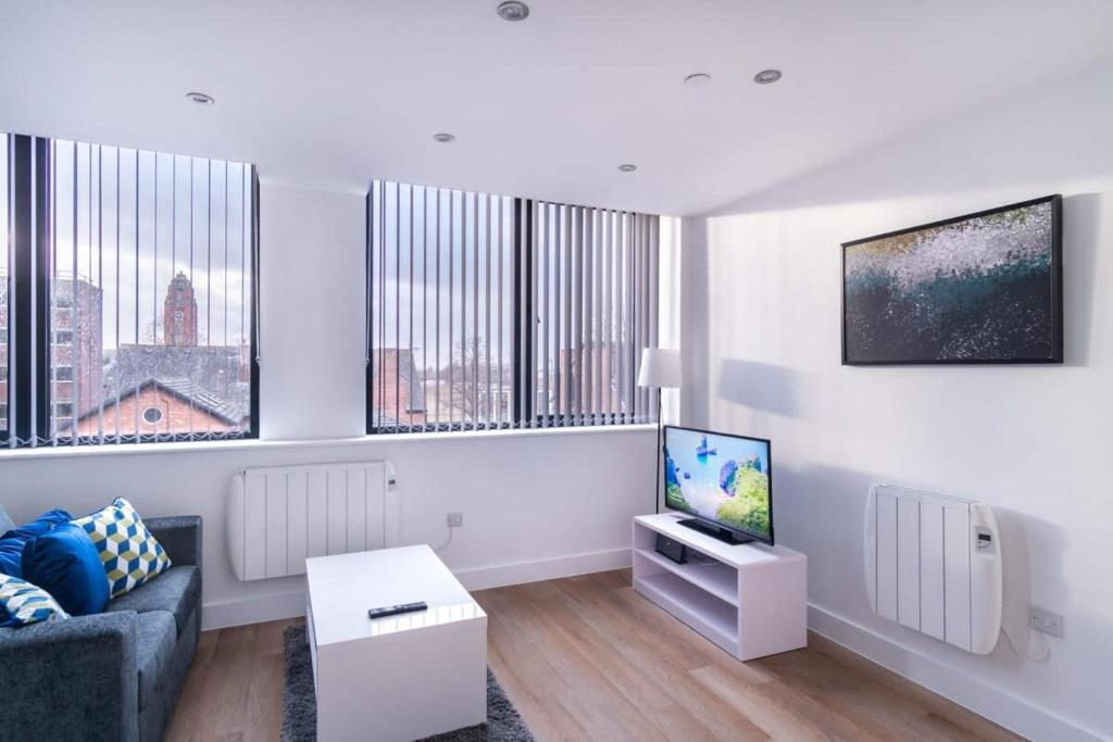 a white living room with a couch and a tv at Spacious 1 Bed Old Trafford Apartment in Manchester