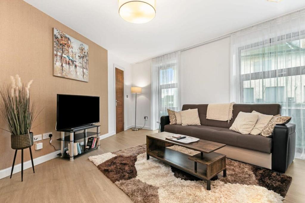 a living room with a couch and a flat screen tv at Modern 1 Bedroom Apartment in Woking Town Centre in Woking