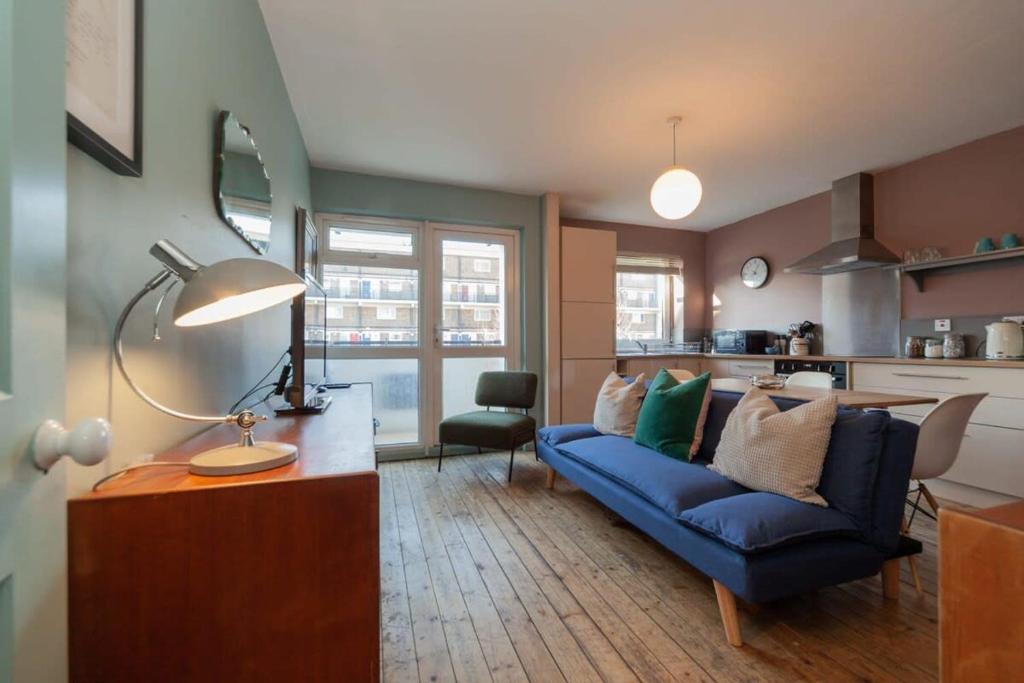 uma sala de estar com um sofá azul e uma cozinha em Centrally Located 4 Bedroom London Apartment em Londres