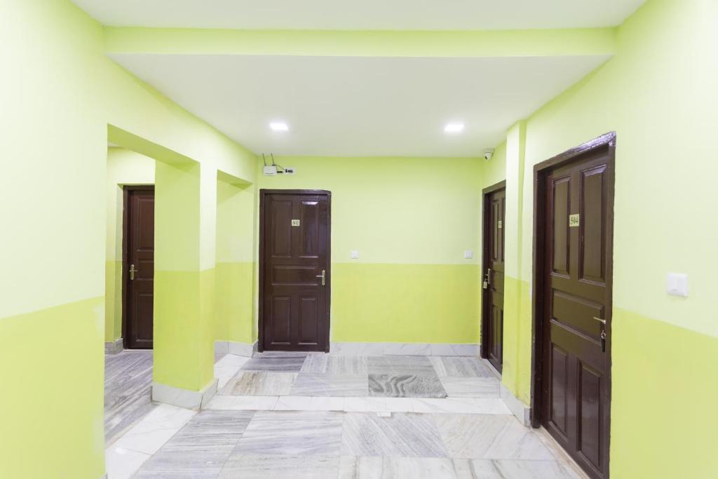 einen Flur mit drei Türen und grünen und weißen Wänden in der Unterkunft OYO Maple The Residence in Thākurdwari