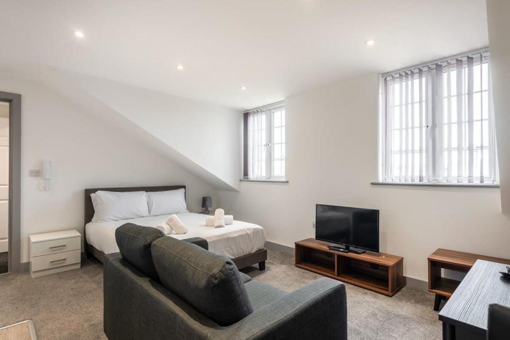 a bedroom with a bed and a couch and a tv at Smart Budget Studio Apartment in Central Doncaster in Doncaster