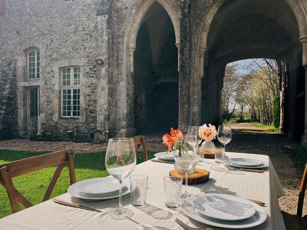 a table with plates and wine glasses in front of a building at ABBAYE DE BLANCHELANDE in Neufmesnil