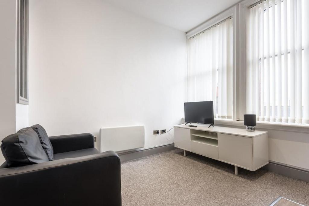 ein Wohnzimmer mit einem Sofa und einem Schreibtisch mit einem TV in der Unterkunft Lovely 1 Bed Budget Apartment in Central Darlington in Darlington