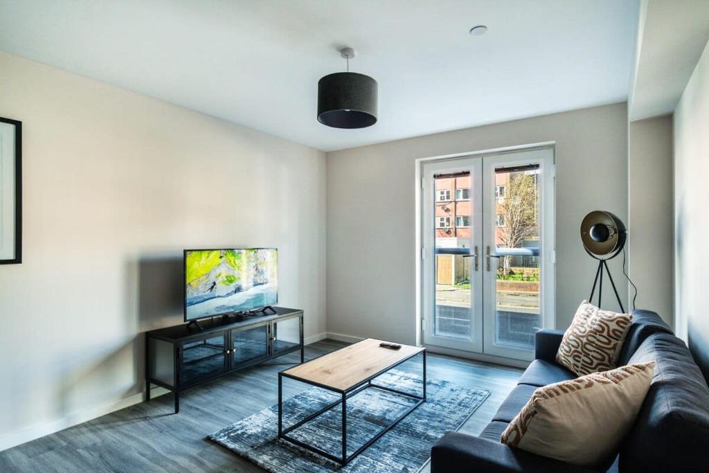 ein Wohnzimmer mit einem Sofa und einem TV in der Unterkunft Spacious & Modern 2 Bed Apartment in Manchester in Manchester