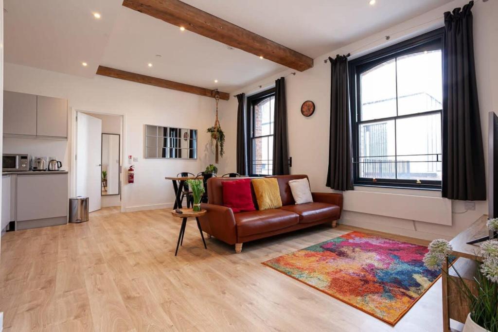 a living room with a leather couch and a rug at Superb 2Bed 2Bath 5min walk to Victoria Station in Manchester