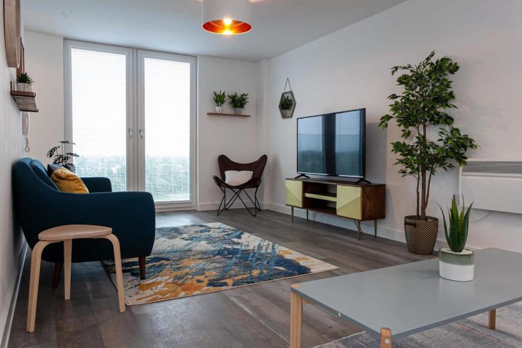 sala de estar con sofá azul y TV en Amazing 2 Bed Apartment 5min To Old Trafford, en Mánchester