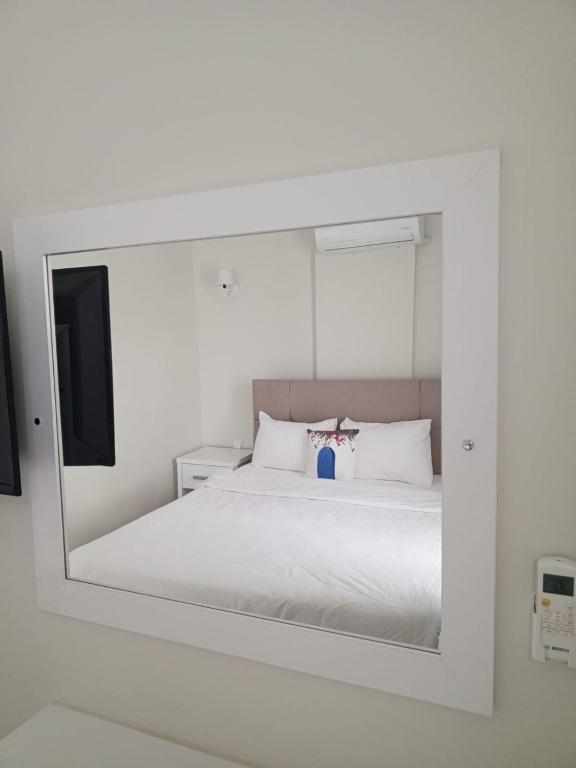 a mirror reflecting a bed in a white bedroom at Port Hotel, Tasucu in Silifke