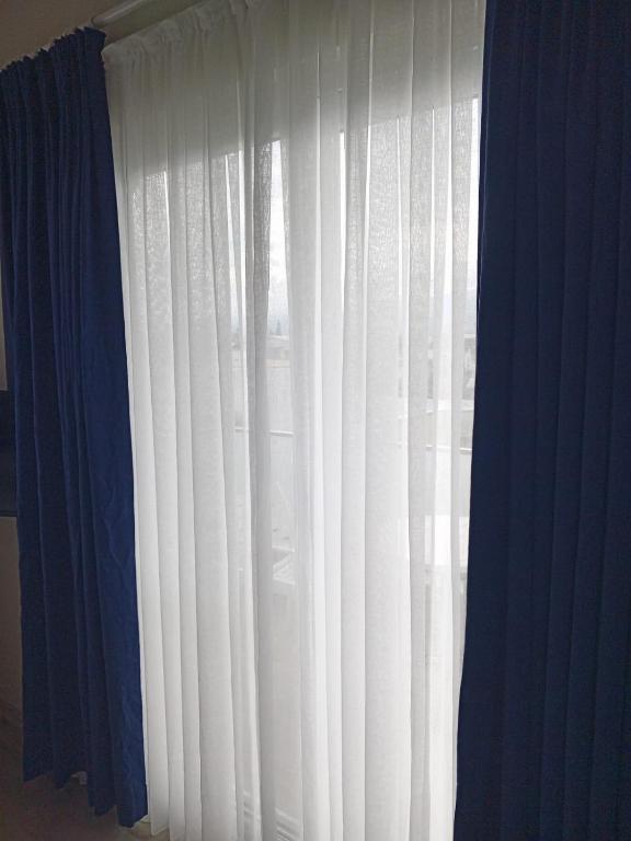 a window with white curtains and a blue at Port Hotel, Tasucu in Silifke