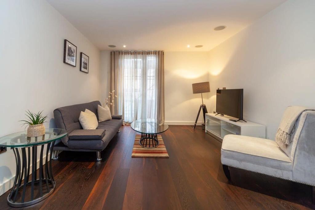 ein Wohnzimmer mit einem Sofa und einem TV in der Unterkunft Spacious and Modern 1 Bedroom Apartment in Chelsea in London