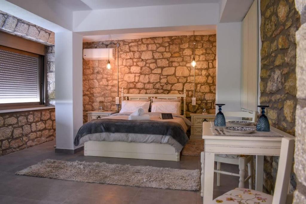 una camera con letto e parete in pietra di Coastal Stone Hideaway with Stunning Scenery a Kitriaí