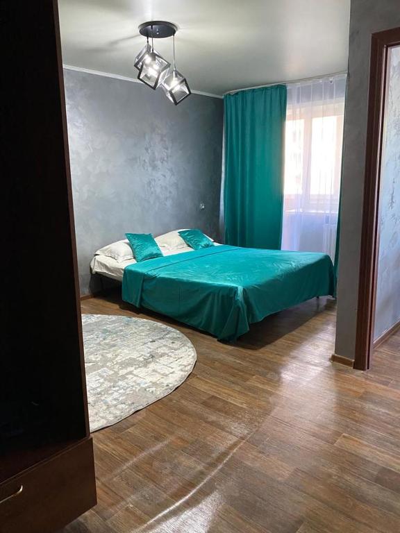 a bedroom with a green bed and a mirror at Тәуелсіздік 89, 1 комнатные апартаменты комфорт класса в центре от компании Home Hotel in Kostanay