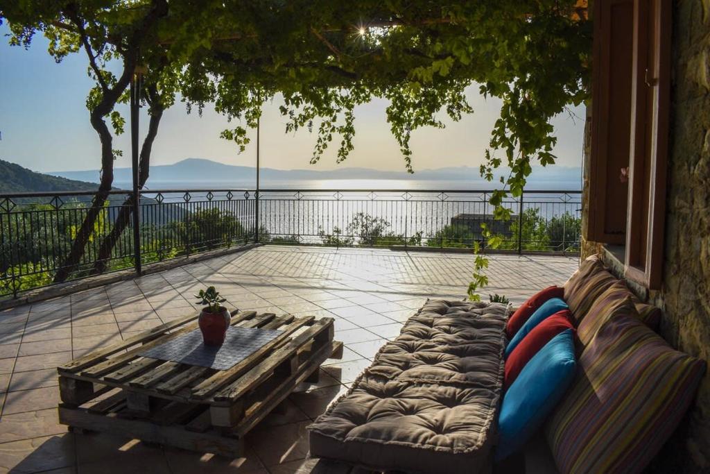 a patio with a couch and a table on a balcony at Coastal Stone Residence with Spectacular Scenery in Kitriaí