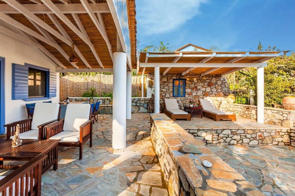 d'une terrasse avec des chaises et un mur en pierre. dans l'établissement The Blue House Seaside Retreat - Fully equipped, à Chrani