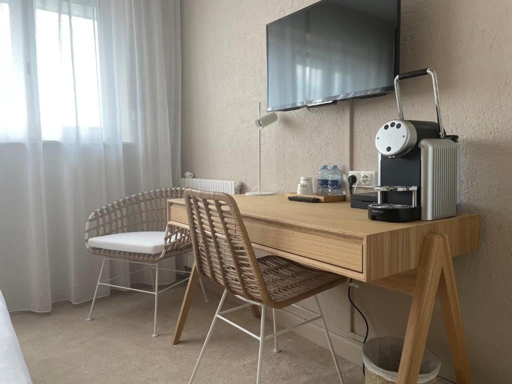 a desk with a coffee maker and chairs in a room at Hôtel Restaurant BO &amp; MIA in La Baule