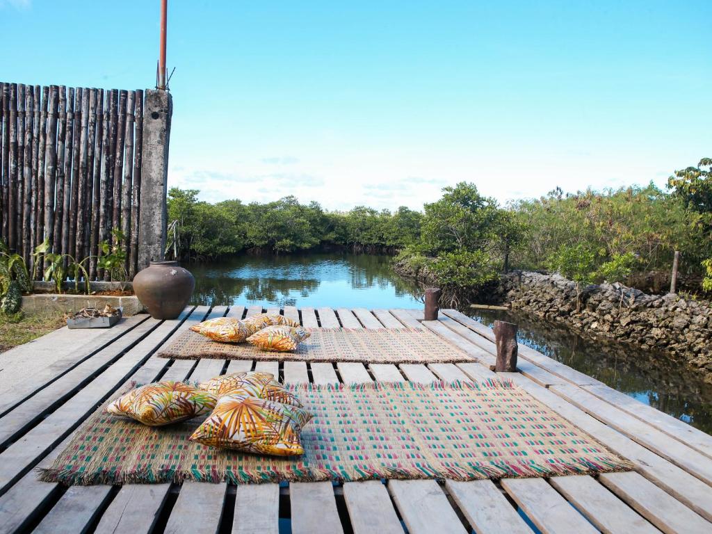 NOGS Homestay, near Magpupungko, Siargao Island Surfings Spots في Pilar: وسادتين جالستين على سطح خشبي بجوار نهر