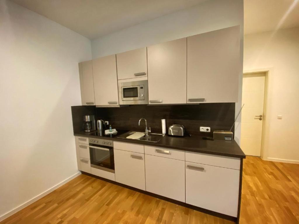 une cuisine avec des armoires blanches et un comptoir noir dans l'établissement Apartments am Kaisersaal, à Erfurt