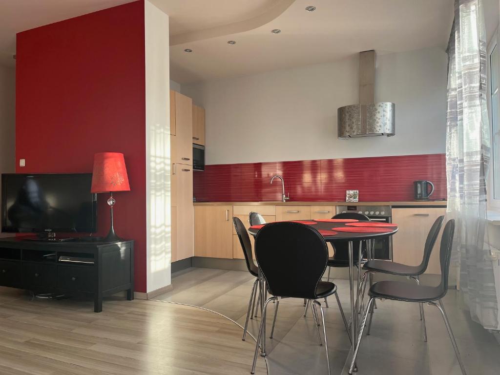 a kitchen with a table and chairs and a red wall at Apartament z ogródkiem in Rewal