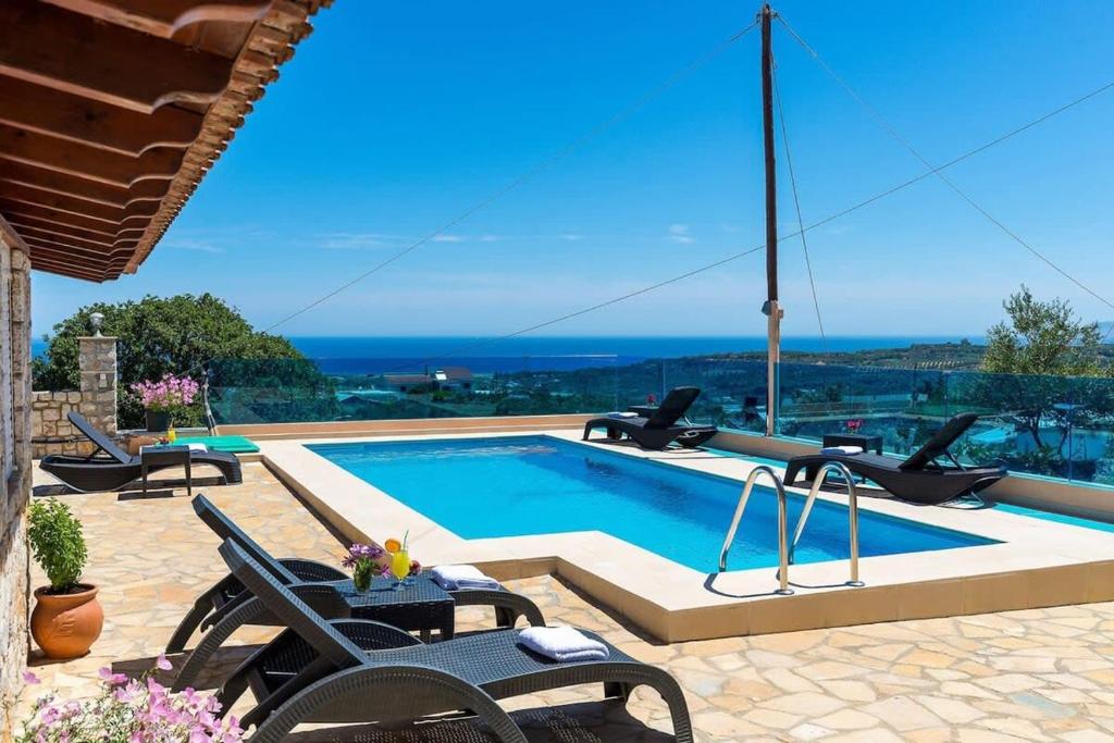 a swimming pool with two chairs and a table next to it at Sea Breeze & Stunning Views - Pool Dream Gem in Dhémbla