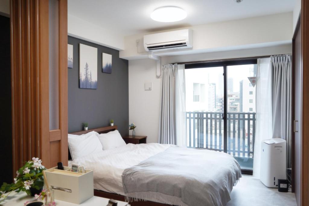 a bedroom with a white bed and a balcony at The Peak Chiyozaki in Osaka