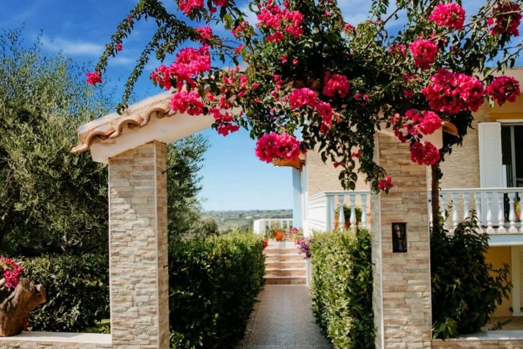 ein Torbogen, der zu einem Haus mit rosa Blumen führt in der Unterkunft Skafidia Seaview Retreat - Orpheas Seaview Home in Skafidia