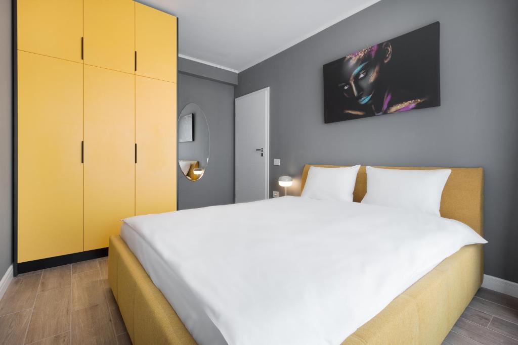 a bedroom with a large white bed and yellow cabinets at Maniu Flats in Oradea
