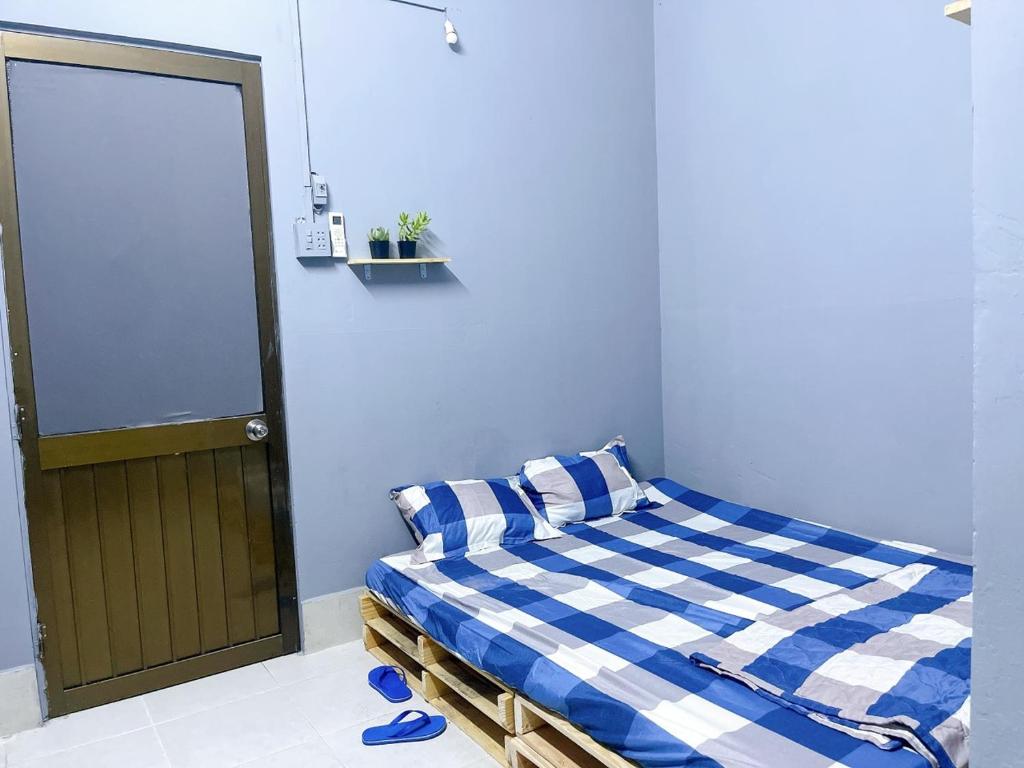 1 dormitorio con 1 cama con manta blanca y azul a cuadros en Nhà Nghỉ Thành Đạt, en Can Tho