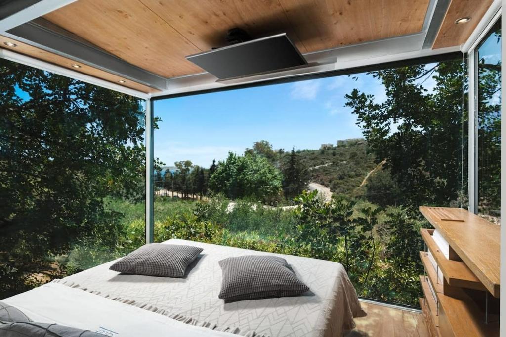 um quarto com uma cama e uma grande janela de vidro em Luxury TreeHouse - A breath away from the beach em Loutrákion