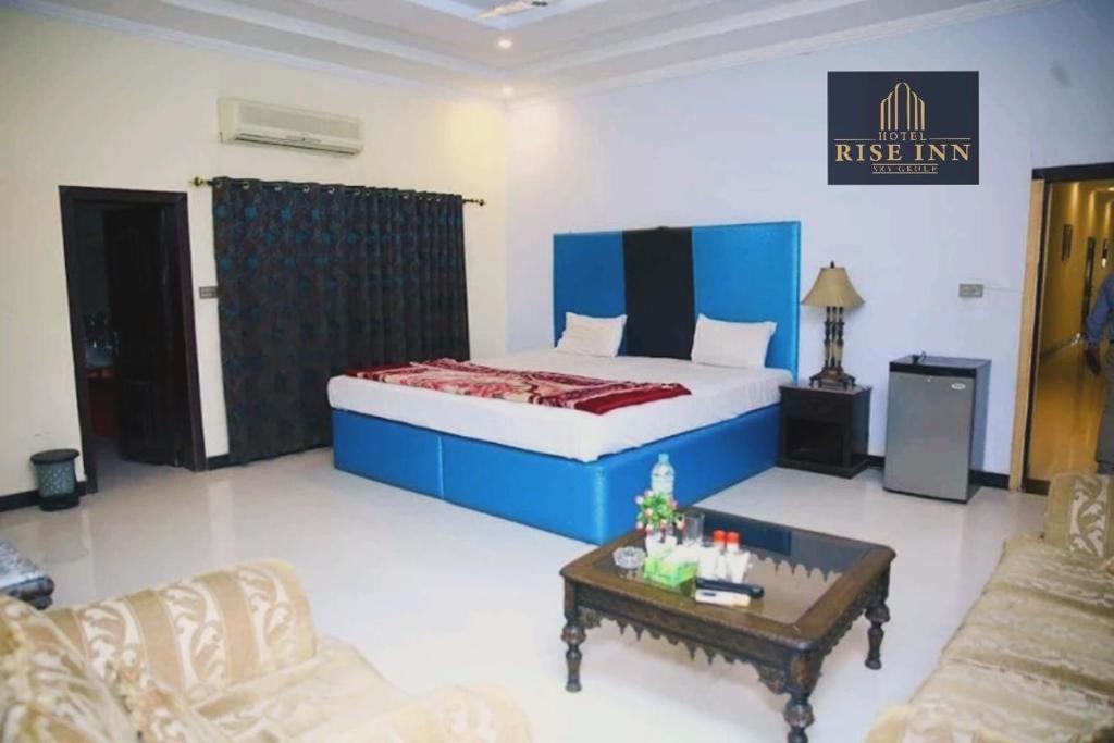 Schlafzimmer mit einem Bett und einem Couchtisch in der Unterkunft Hotel Rise Inn in Karatschi
